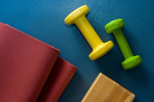 High angle view of dumbbells with exercise mat on table