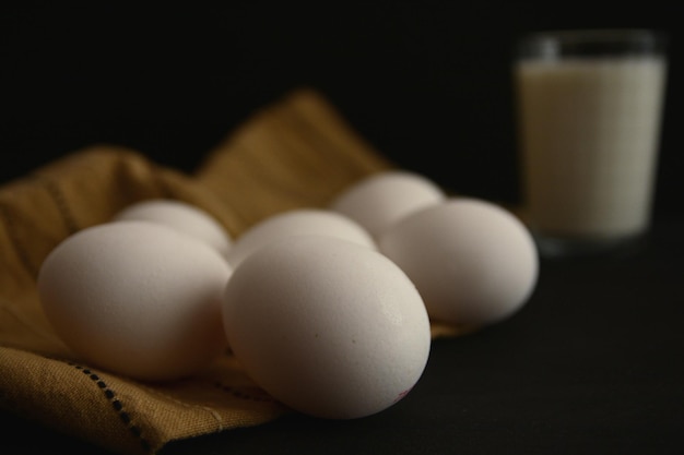 high angle view of eggs and fabric with drink against black background