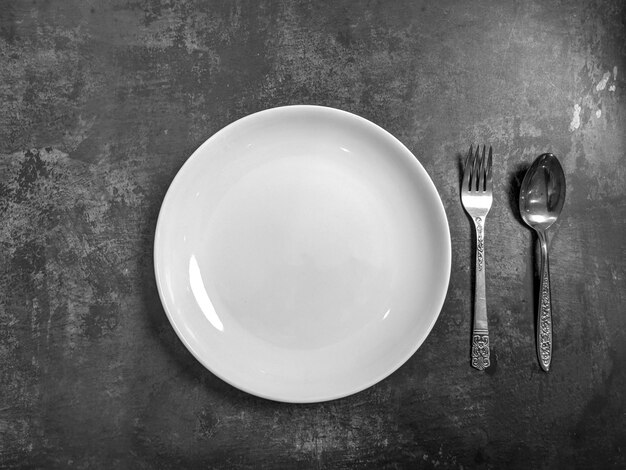 Photo high angle view of empty plate with fork and spoon on table