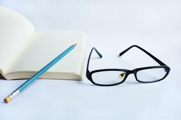 High angle view of eyeglasses and pencil on white background