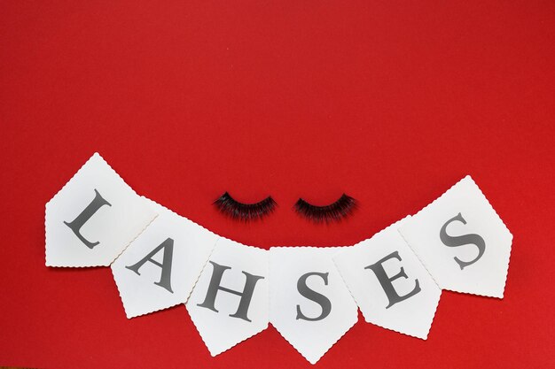 Photo high angle view of false eyelashes by text against red background