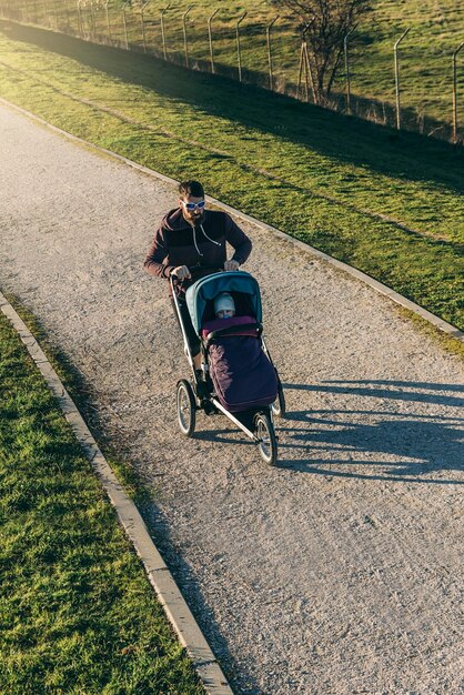 Foto vista ad alta angolazione del padre che spinge il bambino nel passeggino