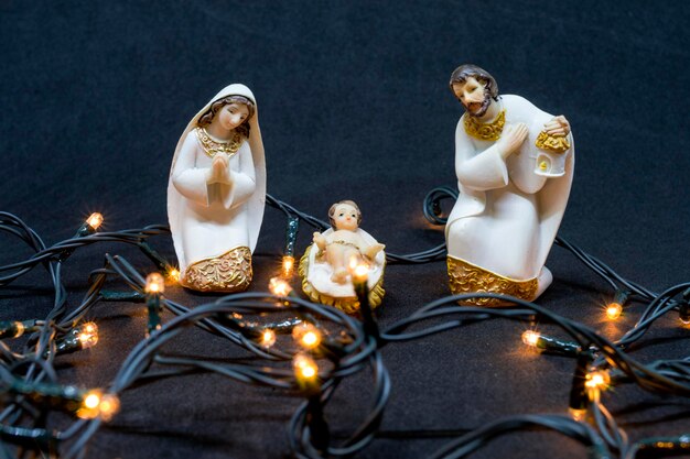 High angle view of figurines and christmas lights on black table