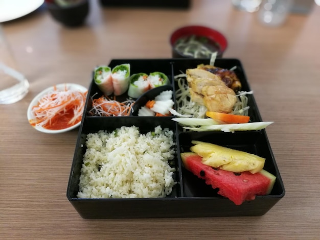 Высокоугольный вид еды в обеденной коробке на столе