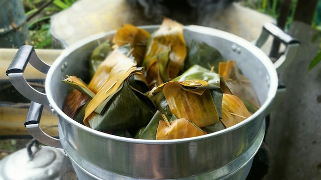 野外でパンで調理されているバナナの葉に包まれた高角度の食べ物