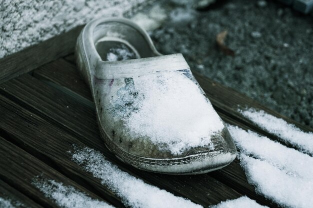 Foto vista ad alto angolo di calzature su legno dalla neve