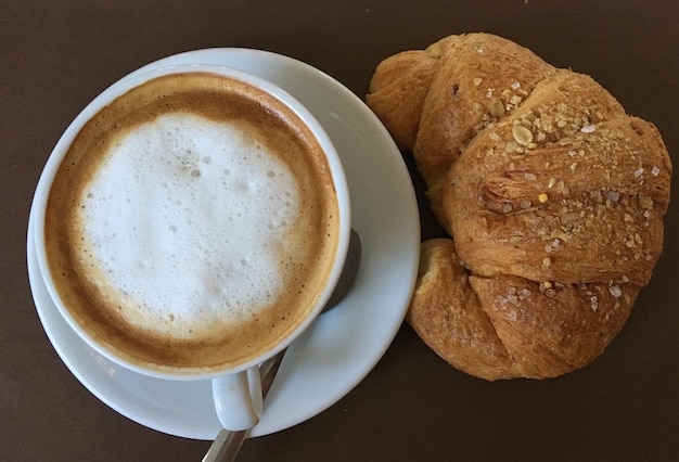 Foto vista ad alta angolazione di caffè fresco e croissant