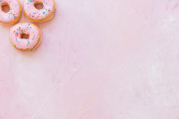 Foto vista dell'angolo alto delle ciambelle fresche con spruzza su fondo rosa