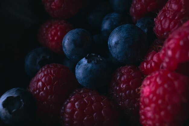 Photo high angle view of fresh raspberries and blueberries in low light