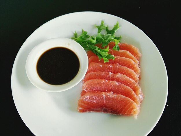 High angle view of fresh salmon served with sauce on black background