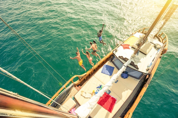 Foto vista ad alta angolazione di amici che saltano da una barca in mare