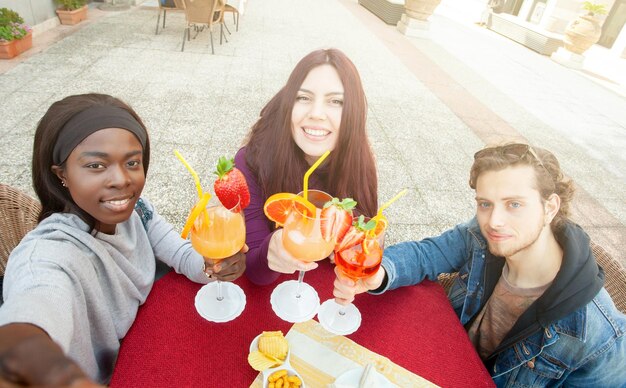 High angle view of friends toasting drinks while sitting at sidewalk cafe