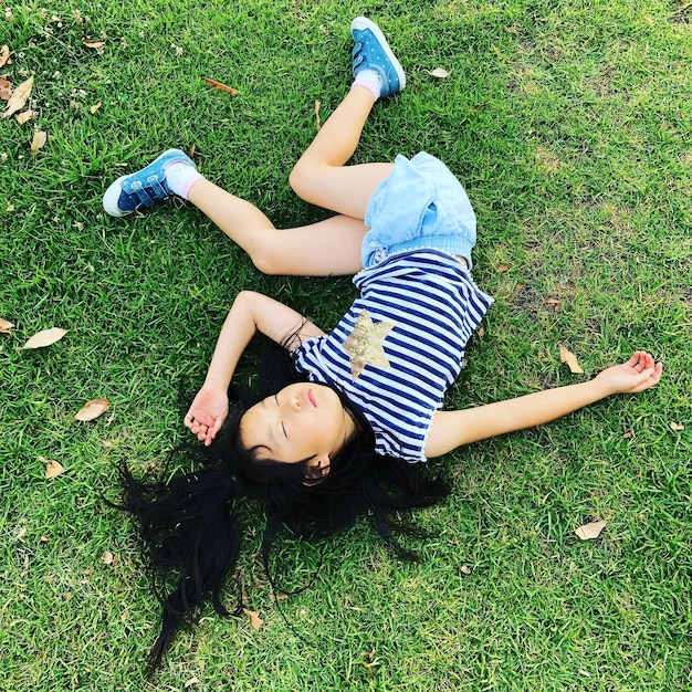 Photo high angle view of girl lying on grassy field