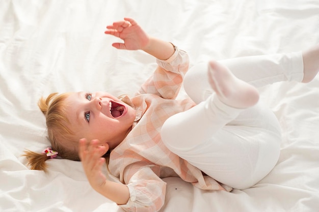 Photo high angle view of girl playing on bed at home