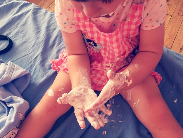 Photo high angle view of girl playing with dough while sitting at home