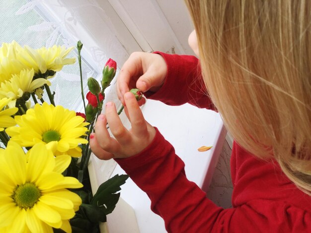 High angle view of girl touching bud at home