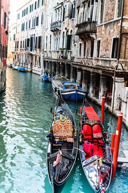 Foto vista ad alto angolo delle gondole ormeggiate nel canale in mezzo agli edifici della città