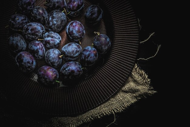 Photo high angle view of grapes in plate against black background