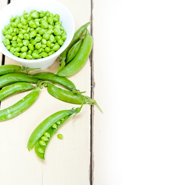 High angle view of green peas by bowl on wooden table