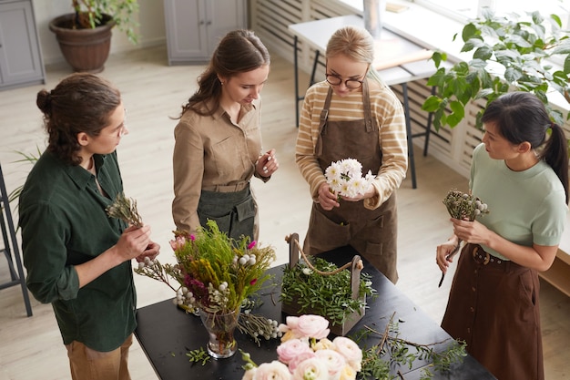 ワークショップ、コピースペースで花の組成物を作成する若い花屋のグループでのハイアングルビュー