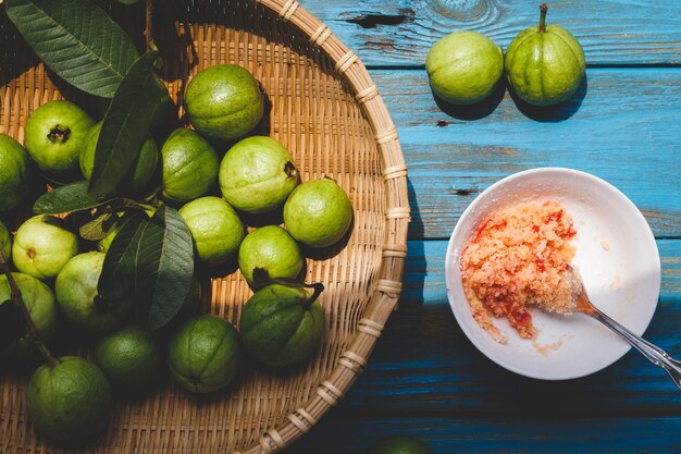 Photo high angle view of guavas in basket by salt in bowl at table