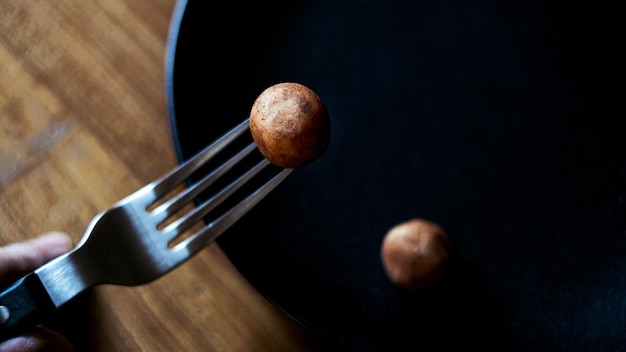 High angle view of hand holding fork with marzipan potatoe on table