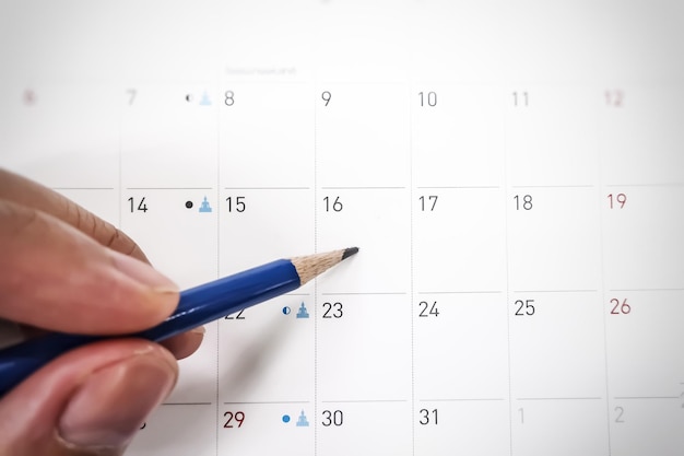 High angle view of hand writing with pencil on calendar