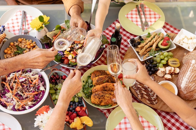 Photo high angle view of the hands of a multi-generation caucasian family holding glasses and making a toast over a table of food outdoors. family enjoying time at home, lifestyle concept