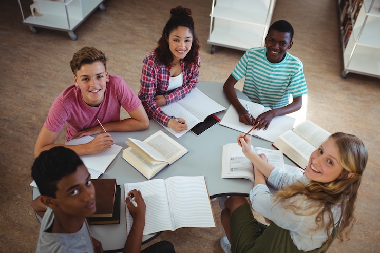 Photo high angle view of happy classmates studying in library