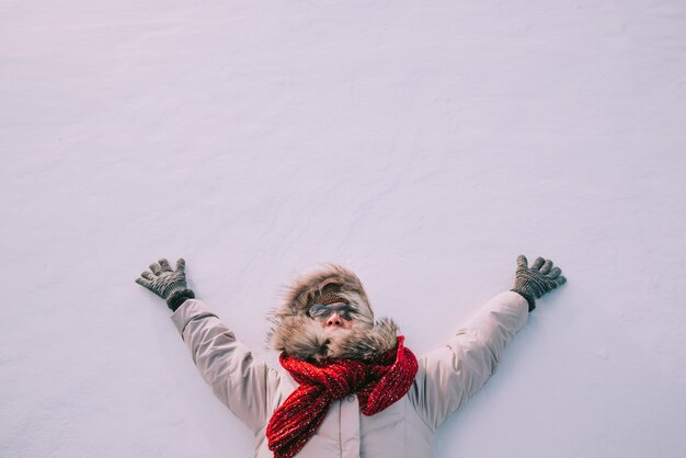 雪の上に横たわる幸せな女の高角度のビュー