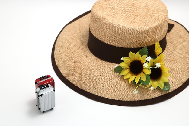 Foto vista ad alta angolazione del cappello con fiori e bagagli su sfondo bianco