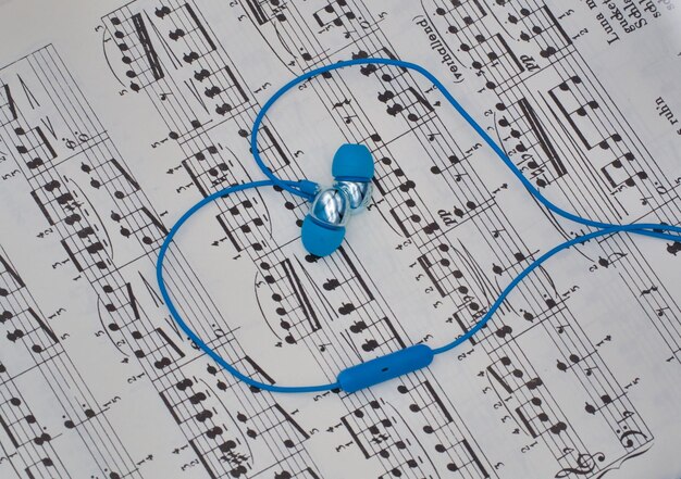 Photo high angle view of heart of earphones on a music sheet