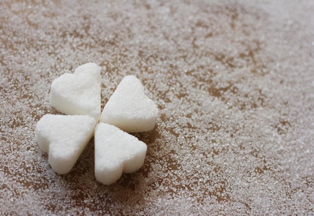 Foto vista ad alta angolazione dello zucchero a forma di cuore su un trifoglio bianco