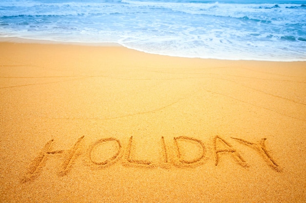 High angle view of holiday text on sand at beach