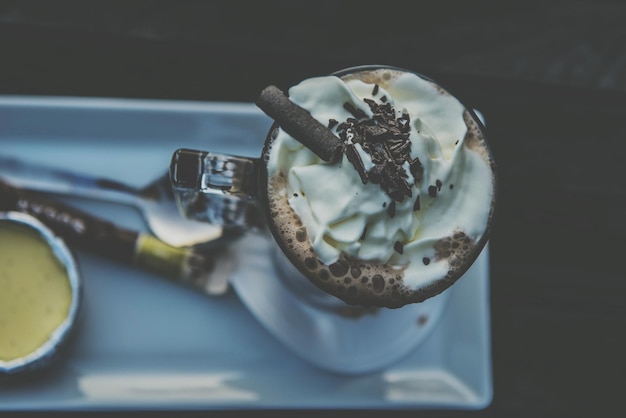 Foto vista ad alto angolo di cioccolato caldo con panna montata in bicchiere sul tavolo