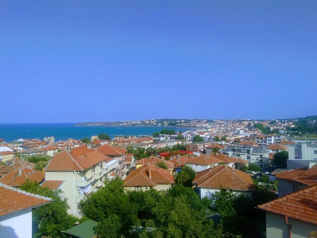 High angle view of houses by sea against clear blue sky