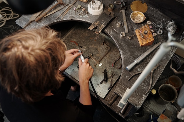 ワークステーションで銀のリングを磨きながら研磨ツールを使用して宝石商の高角度ビュー