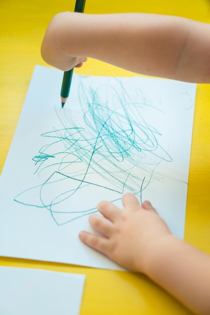Foto vista ad alto angolo di un bambino che scarabocchia su carta al tavolo