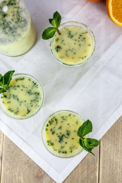 High angle view of kiwi juice in glasses on tablecloth