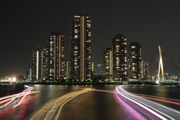 Foto vista ad alta angolazione delle tracce luminose sul fiume contro la città illuminata