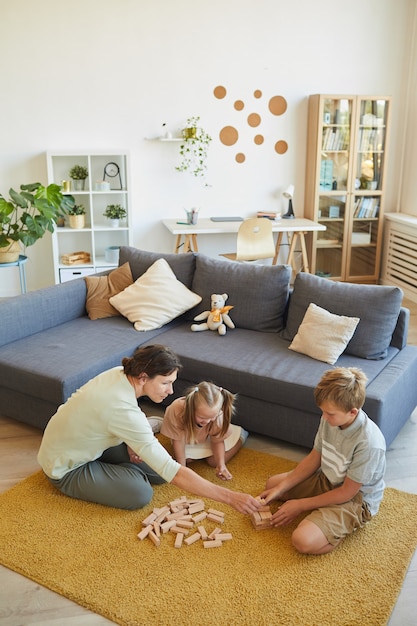 Photo high angle view at loving family with little special needs girl playing board games while sitting on floor at home, copy space