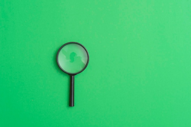 Photo high angle view of magnifying glass over green background