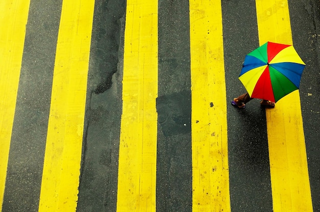 High angle view of man carrying multi colored umbrella while walking on street