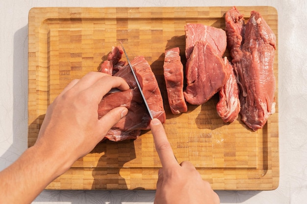 High angle view of a man cutting meat on a wooden board