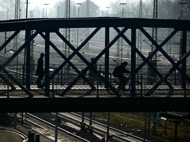 Photo high angle view of man cycling on bridge over road and railroad tracks