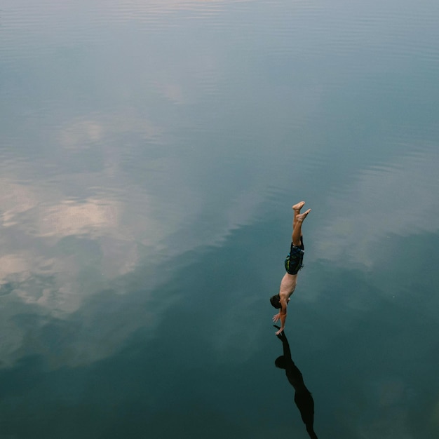 Foto vista ad alta angolazione di un uomo che si tuffa in un lago calmo