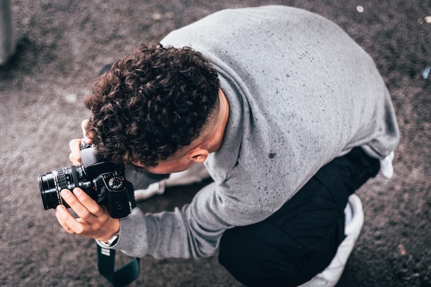 Photo high angle view of man photographing while crouching on road