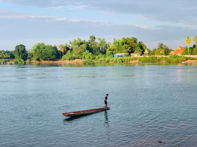 High angle view of man standing on boat in lake against sky