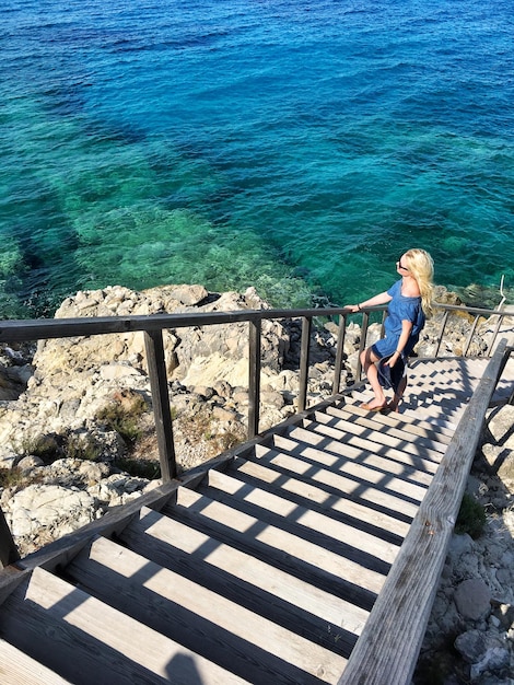 High angle view of man standing on railing by sea