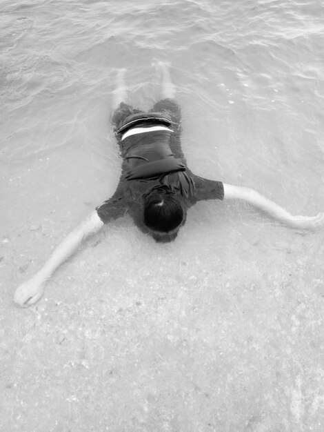 Foto vista ad alta angolazione di un uomo che nuota in acqua sulla spiaggia